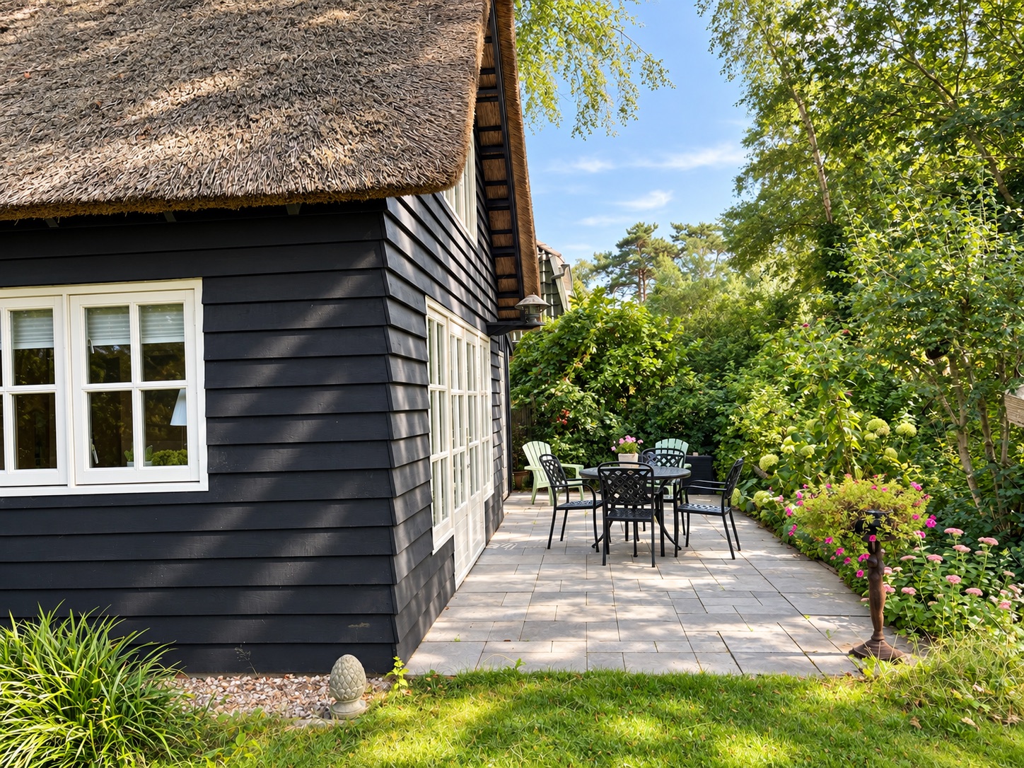 The thatched house and terrace seen from the sunny garden