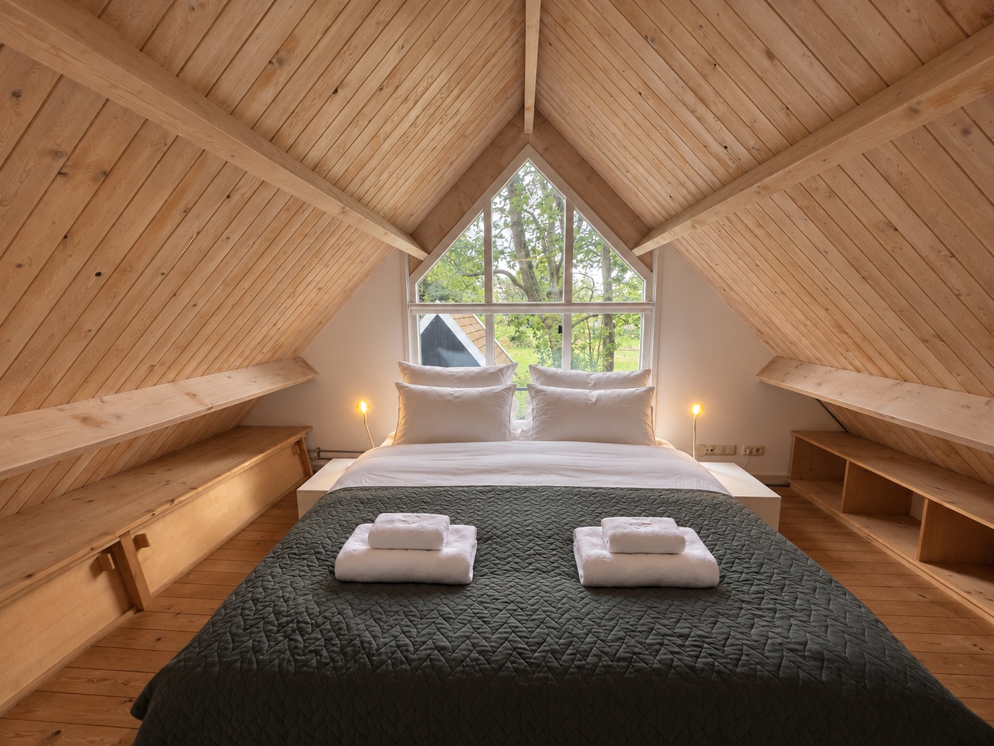 Mezzanine bedroom with wooden beams and the large studio window