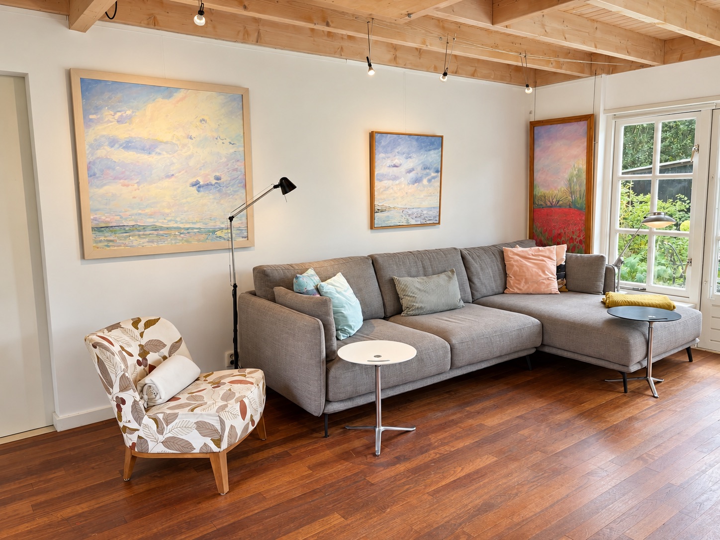 The living room with a light corner sofa, paintings and wooden floor